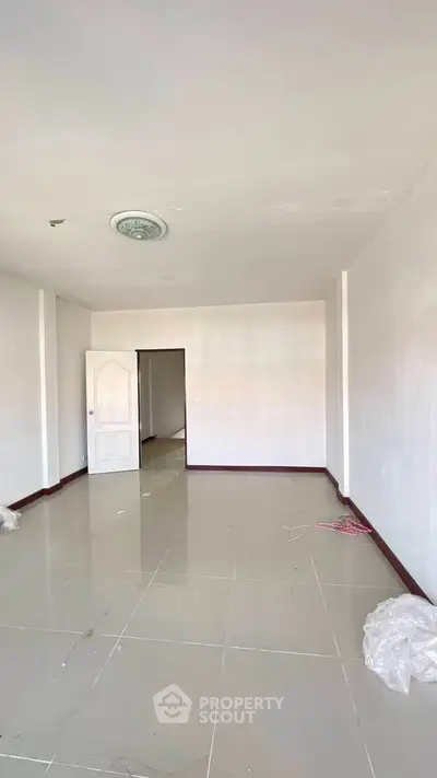 Spacious empty room with tiled flooring and white walls, ready for customization.
