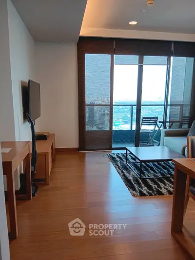 Modern living room with wooden flooring and balcony view in high-rise apartment