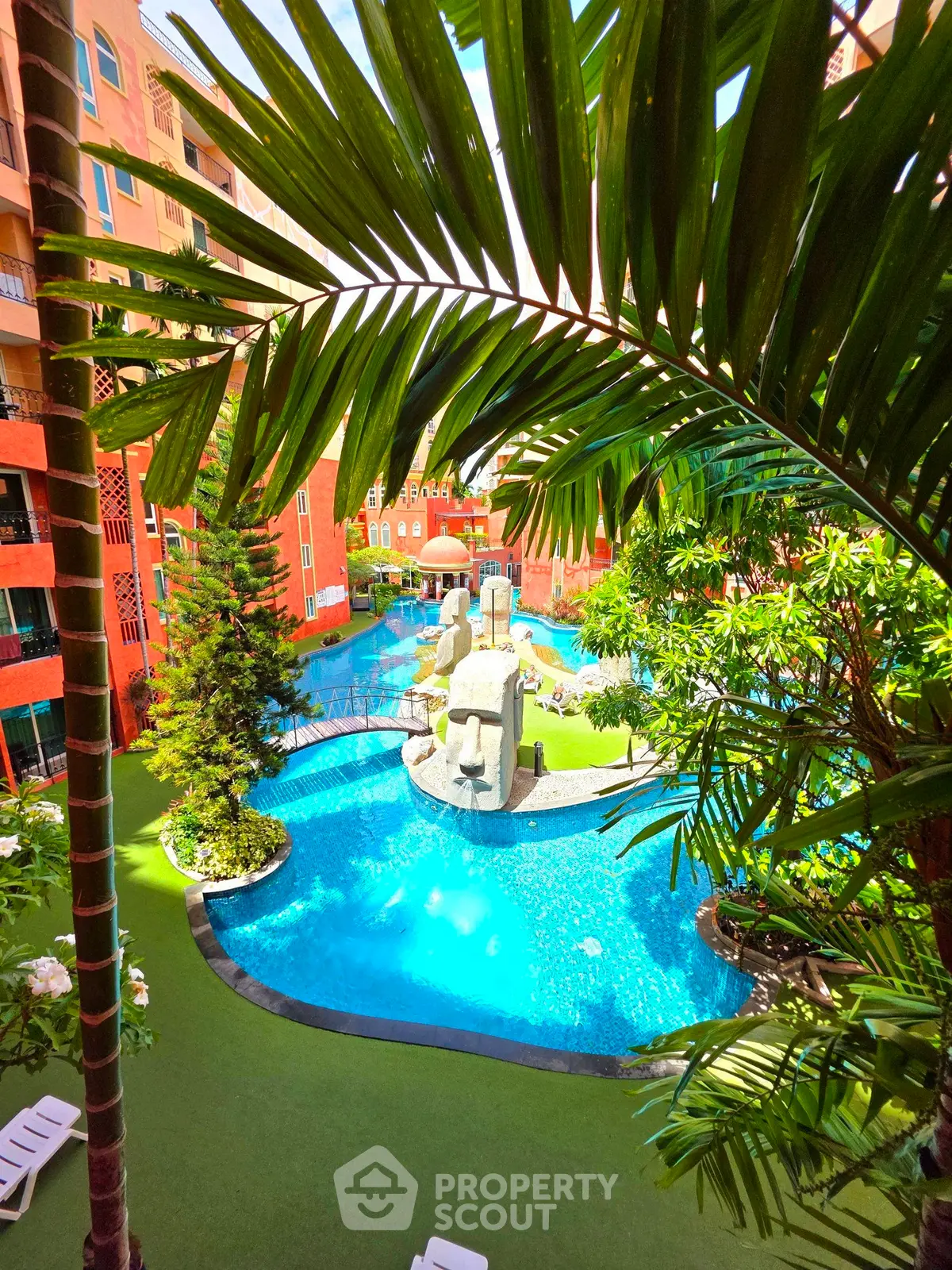 Luxurious resort-style pool with lush greenery and unique sculptures in a vibrant residential complex.