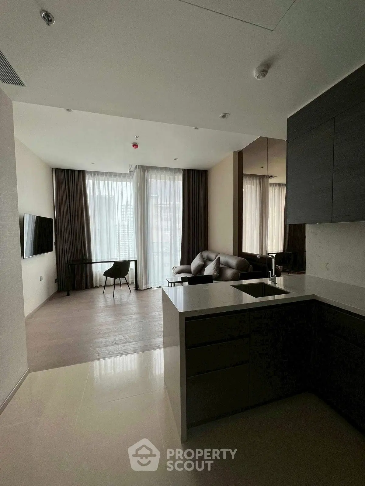 Modern open-plan living room with sleek kitchen and large windows in a stylish apartment.