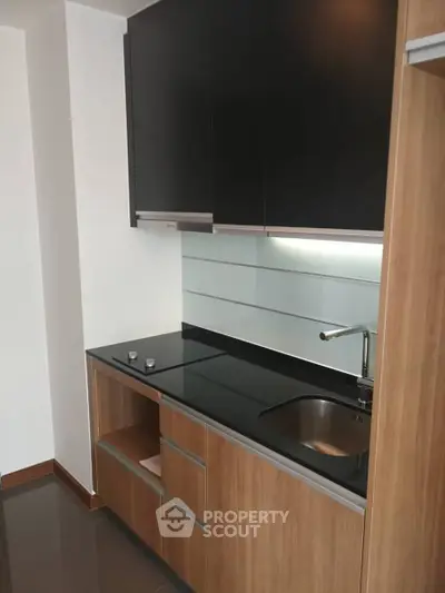 Modern kitchen with sleek black countertops and wooden cabinetry, perfect for contemporary living.