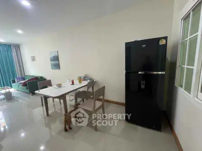 Spacious living area with modern dining set and sleek black fridge