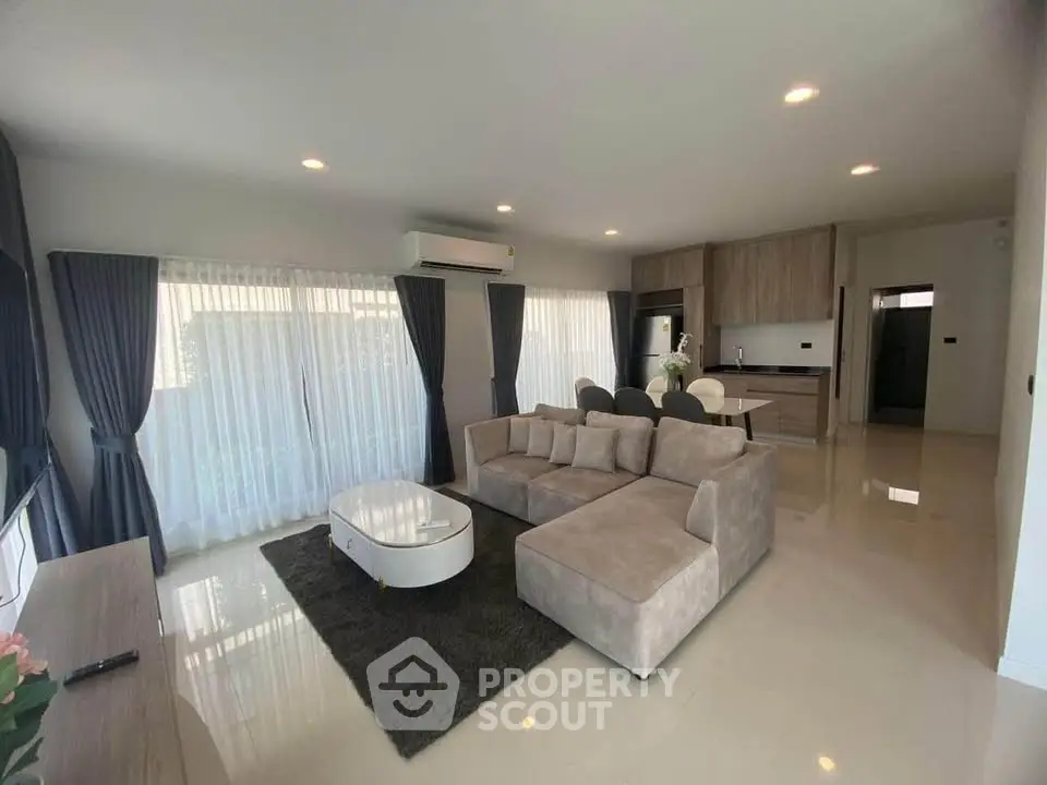 Spacious modern living room with open kitchen, featuring elegant decor and ample natural light.
