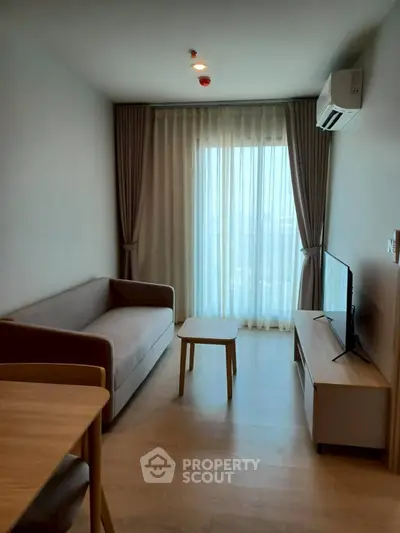 Modern living room with natural light, sleek furniture, and floor-to-ceiling windows.