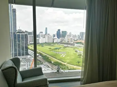 Stunning cityscape view from high-rise apartment window overlooking golf course and skyline.