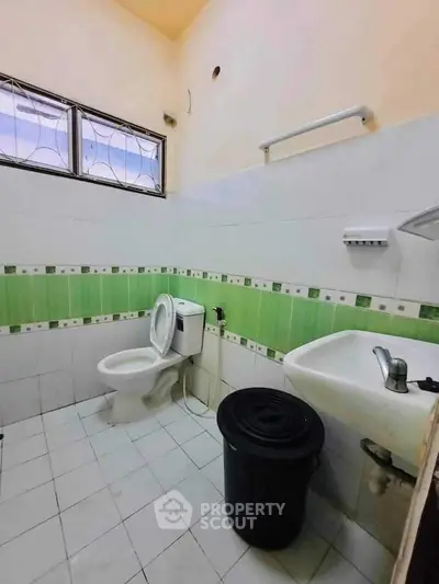 Compact bathroom with green tile accents and basic fixtures