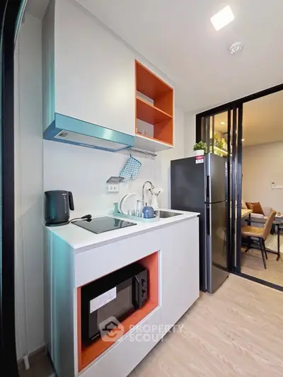 Modern compact kitchen with sleek appliances and open shelving in a stylish apartment.