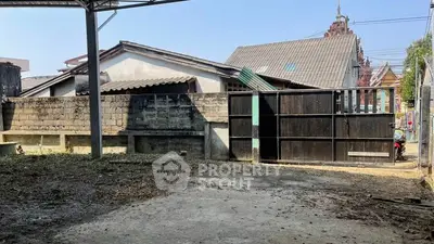 Spacious outdoor area with potential for development, featuring a secure gate and surrounding buildings.