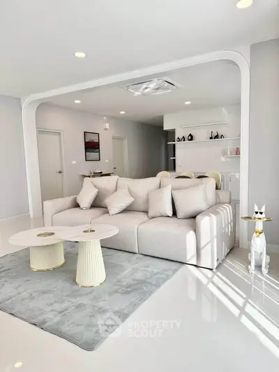Luxurious modern living room with elegant decor and open layout, featuring plush sofa and stylish coffee tables.