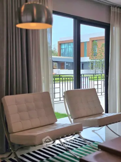 Modern living room with stylish chairs and large window view of contemporary house