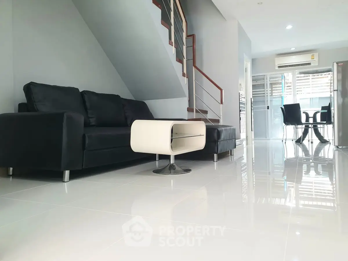 Modern living room with sleek black sofa and glossy white floors