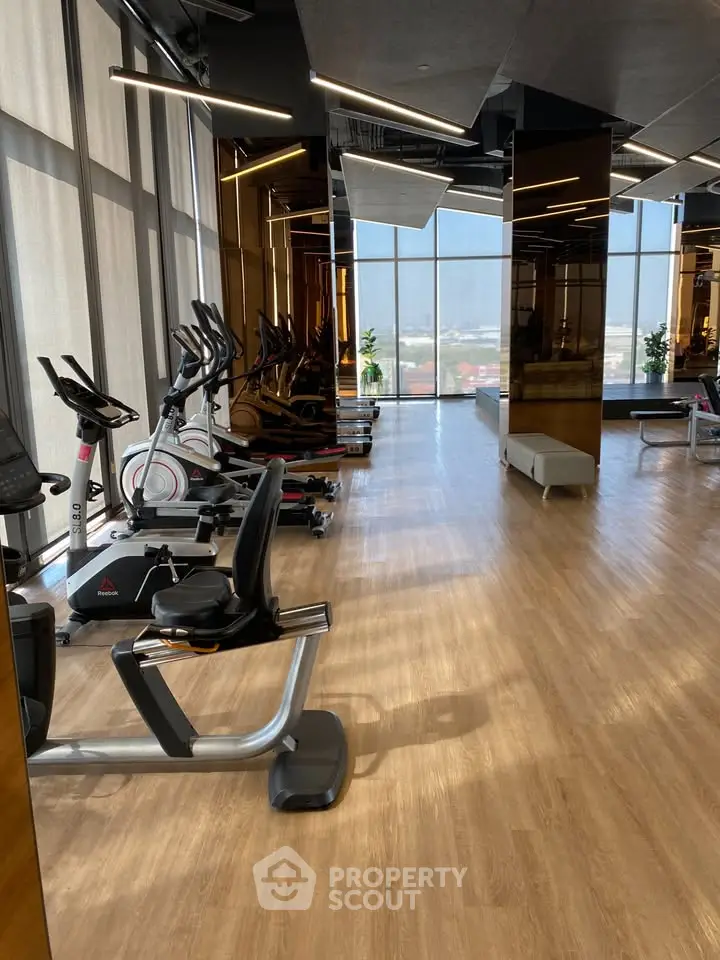 Modern gym with sleek equipment and floor-to-ceiling windows offering a panoramic city view.
