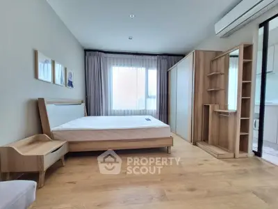 Spacious modern bedroom with wooden furniture and large window, perfect for comfort and relaxation.