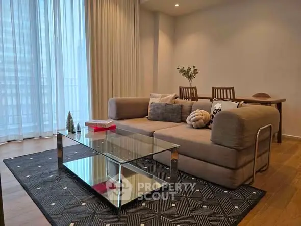 Modern living room with stylish sofa, glass coffee table, and elegant decor in a cozy apartment.