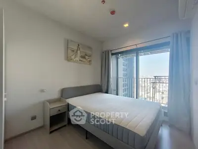 Modern bedroom with large window and city view, featuring a comfortable bed and stylish decor.