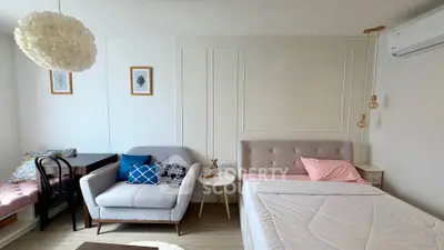 Chic studio apartment with cozy bed, stylish sofa, and modern decor