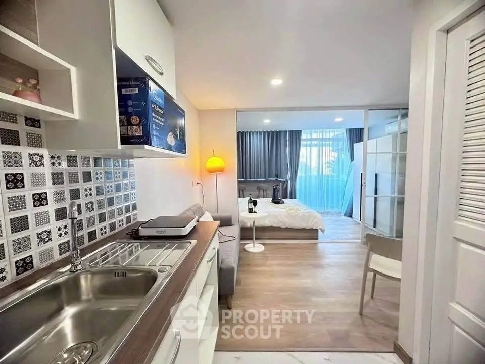 Modern studio apartment with stylish kitchen and cozy bedroom area.