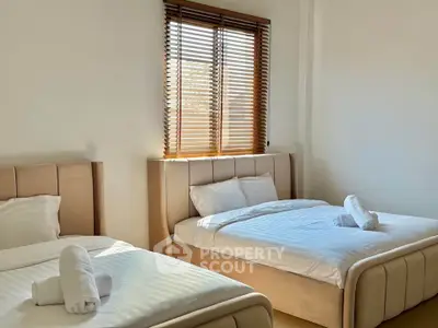 Bright and cozy bedroom with two beds and natural light through window blinds.