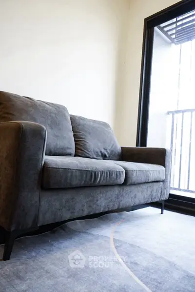 Modern living room with stylish gray sofa and large window for natural light.