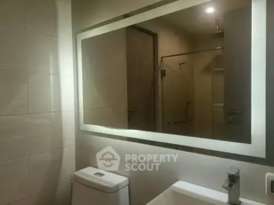 Modern bathroom with illuminated mirror and sleek fixtures in a contemporary apartment.