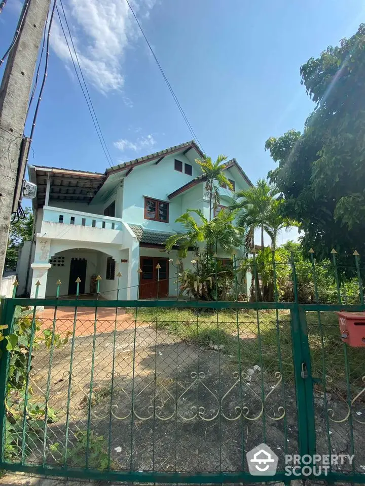 Charming two-story home with lush greenery and a spacious front yard, featuring a large balcony and traditional architectural details.