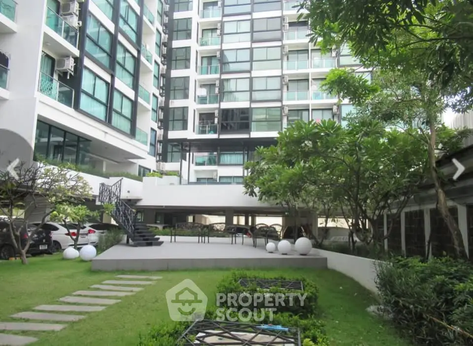 Modern apartment building with lush garden and outdoor seating area