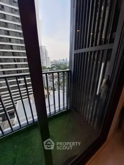 Charming city view from a cozy balcony with modern railing and artificial grass flooring.