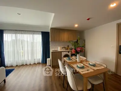 Modern open-plan living room with dining area and kitchen, featuring elegant decor and natural light.