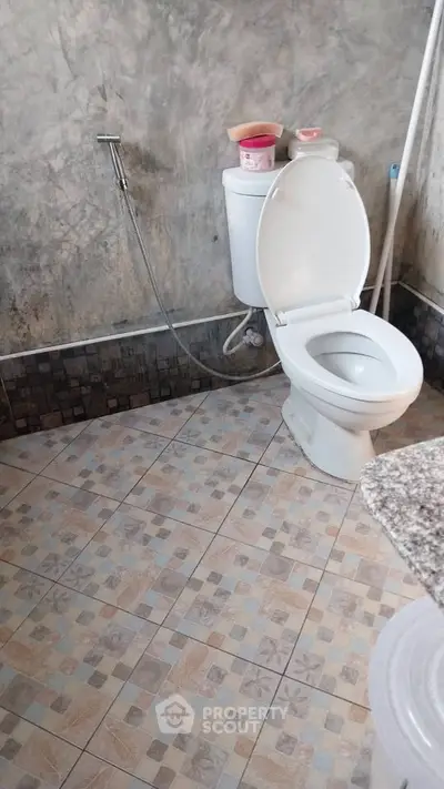 Cozy bathroom with modern toilet and tiled flooring, perfect for a comfortable living space.