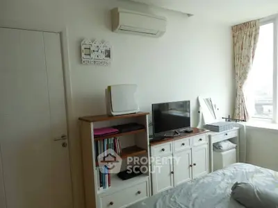 Cozy bedroom with air conditioning and natural light, featuring a TV and bookshelf for a comfortable living space.