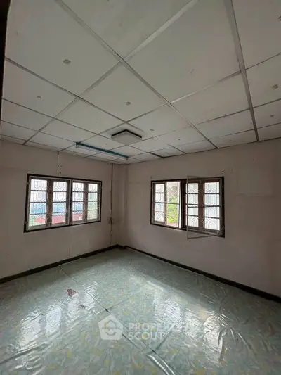 Spacious empty room with tiled floor and large windows, ideal for customization.
