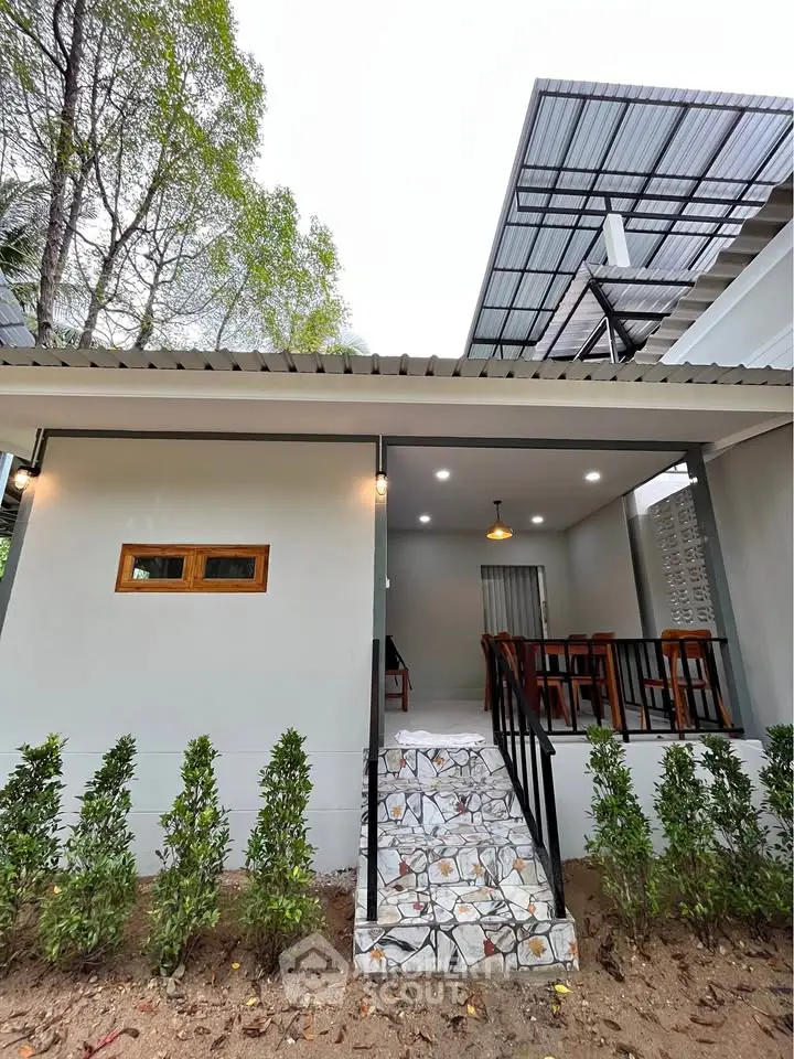 Charming modern home exterior with inviting porch and lush greenery