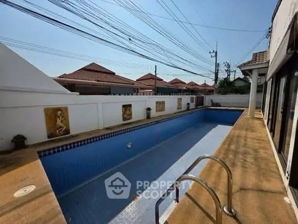 Spacious outdoor pool area in a residential property with clear blue skies.