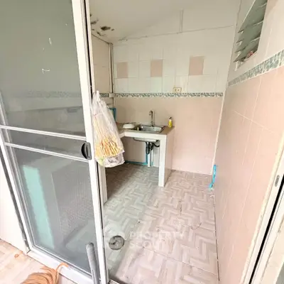 Compact kitchen with tiled walls and sliding glass door in cozy apartment.