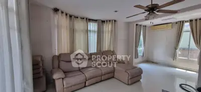 Spacious living room with large windows and cozy sectional sofa, featuring ceiling fan and air conditioning.