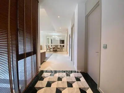 Elegant hallway leading to a spacious living area with modern decor and stylish lighting.