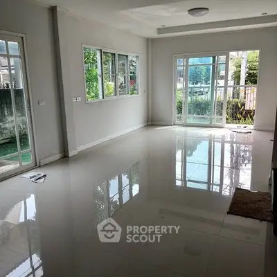 Spacious living room with large windows and glossy tiled floor