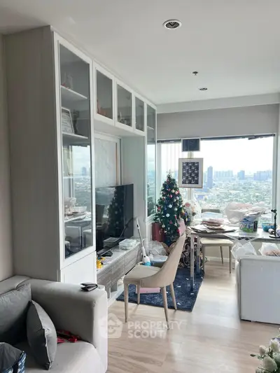 Modern living room with city view, stylish furniture, and a festive Christmas tree.