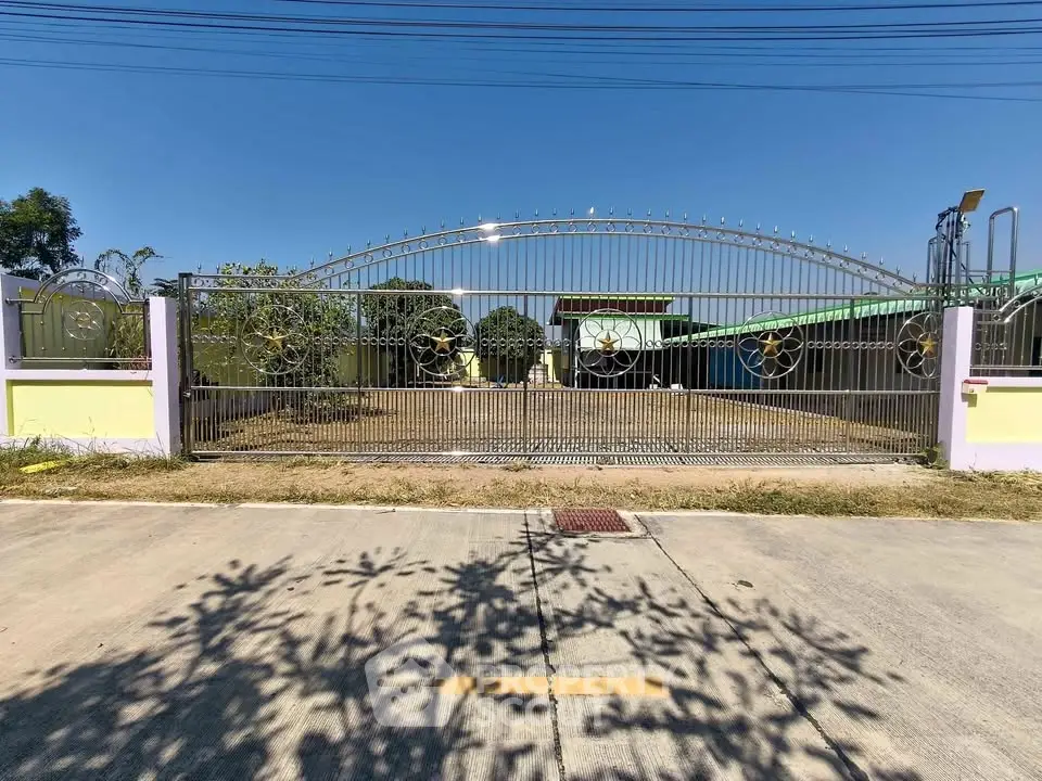 Spacious gated property with expansive driveway and clear blue sky.