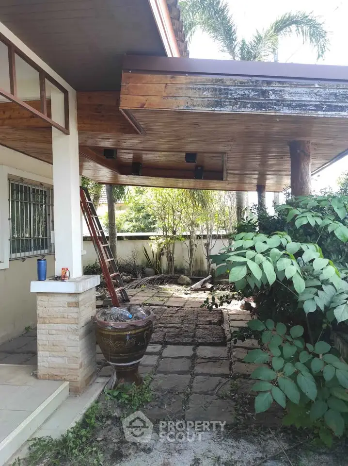 Charming garden patio with rustic wooden roof and lush greenery