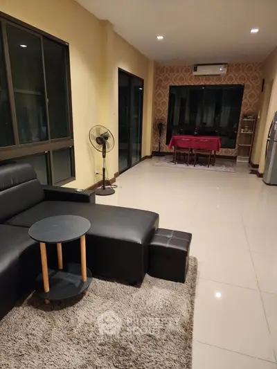 Spacious living room with modern furniture and dining area, featuring large windows and elegant decor.