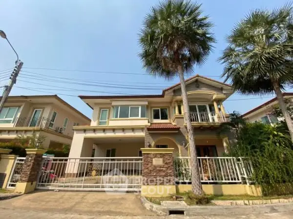 Charming two-story house with palm trees and gated entrance in a serene neighborhood.