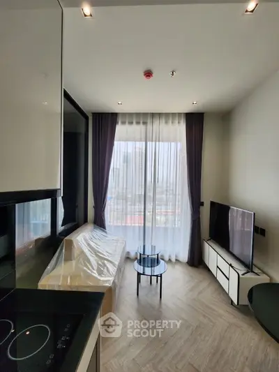 Modern living room with city view, featuring sleek furniture and floor-to-ceiling windows.