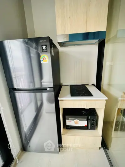 Modern kitchen with sleek appliances including fridge, stove, and microwave in compact layout.