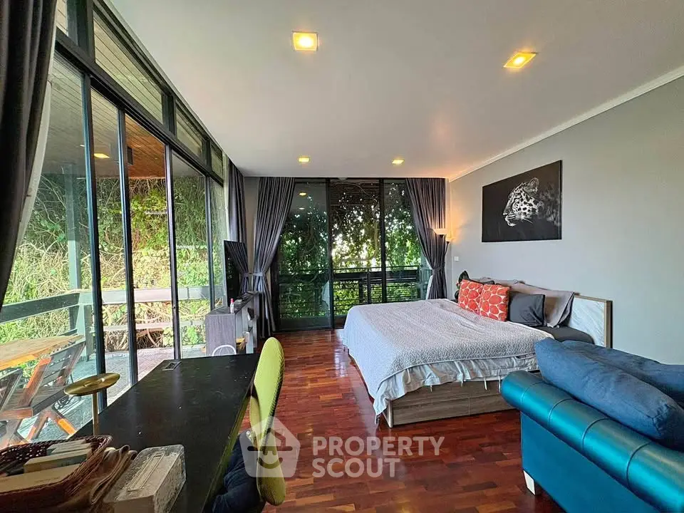 Spacious bedroom with large windows and balcony offering lush green views, perfect for serene living.