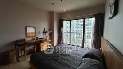 Spacious bedroom with large window offering city views, featuring modern furniture and ample natural light.