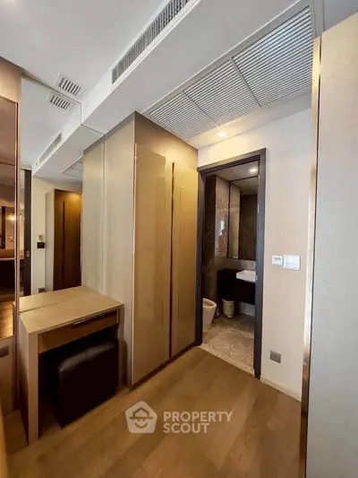 Modern apartment hallway with elegant wooden flooring and sleek bathroom entrance.