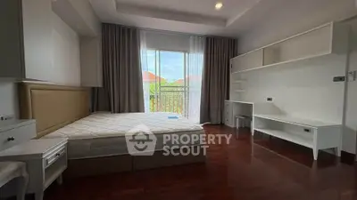 Spacious bedroom with large window and built-in shelves, offering a bright and airy atmosphere.