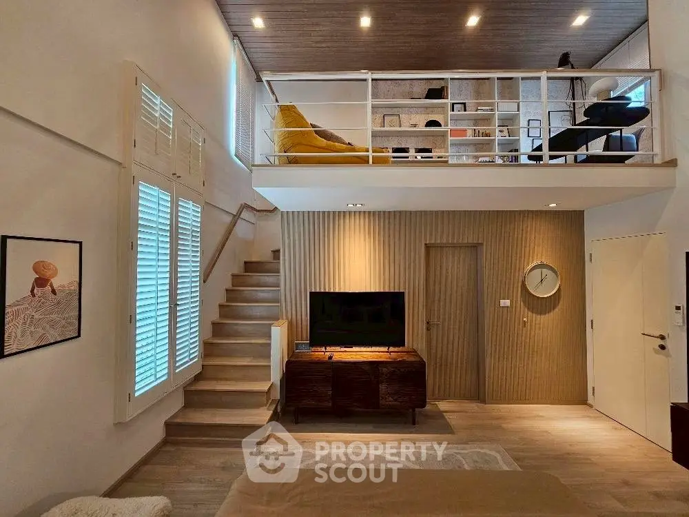 Modern loft-style living room with mezzanine, stylish decor, and natural light.