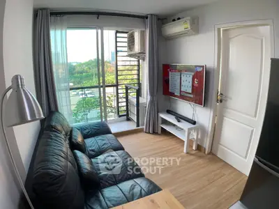 Modern living room with balcony view, black leather sofa, and wall-mounted TV in a cozy apartment.